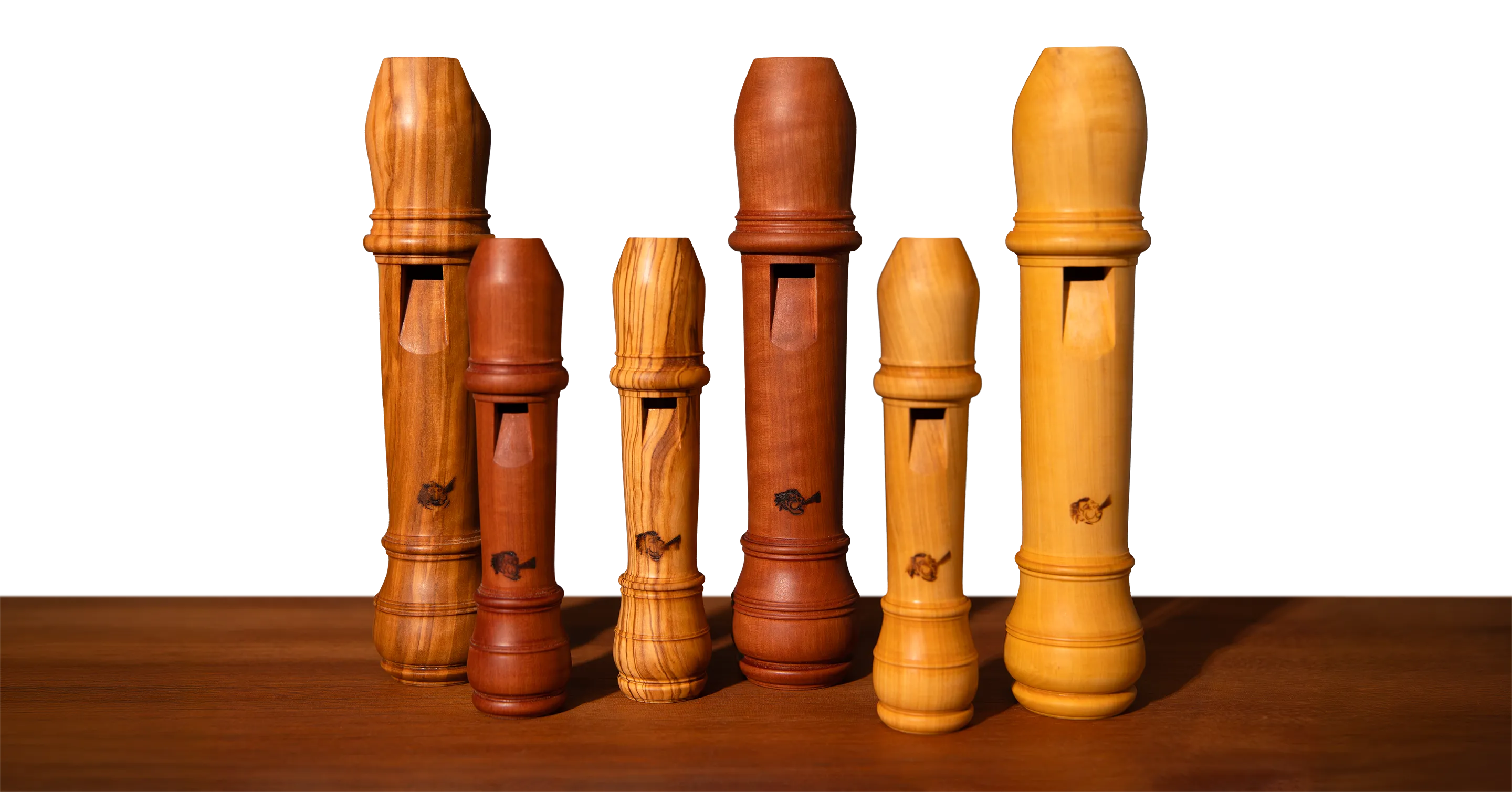 Têtes de flûtes à bec en différents bois, alignées sur l'établi de l'atelier